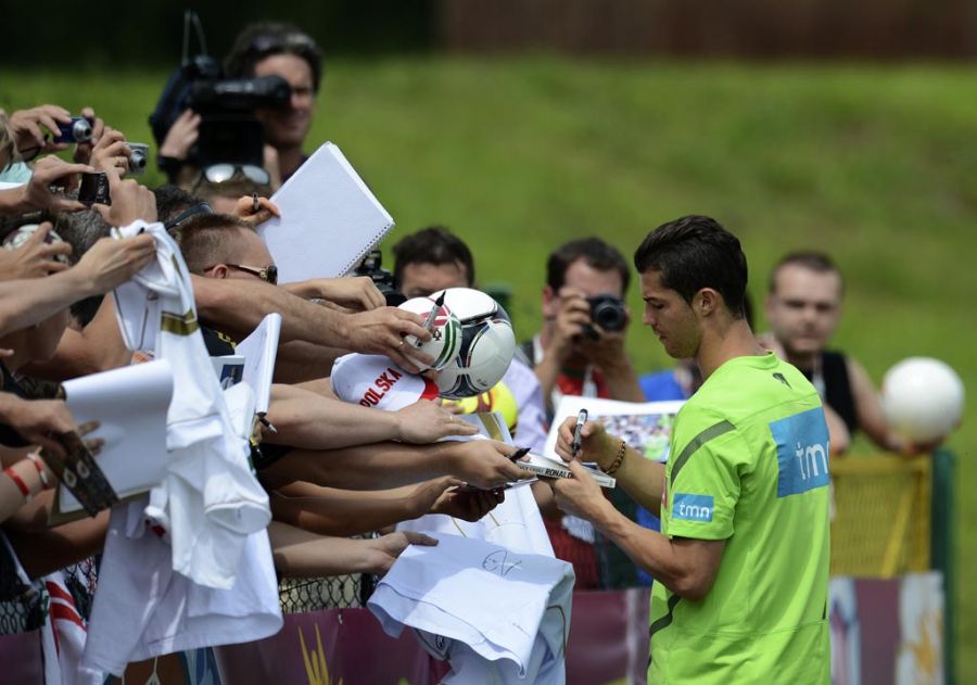Cristiano Ronaldo dá autógrafos durante treino da seleção portuguesa: atacante animado / Francisco Leong/AFP