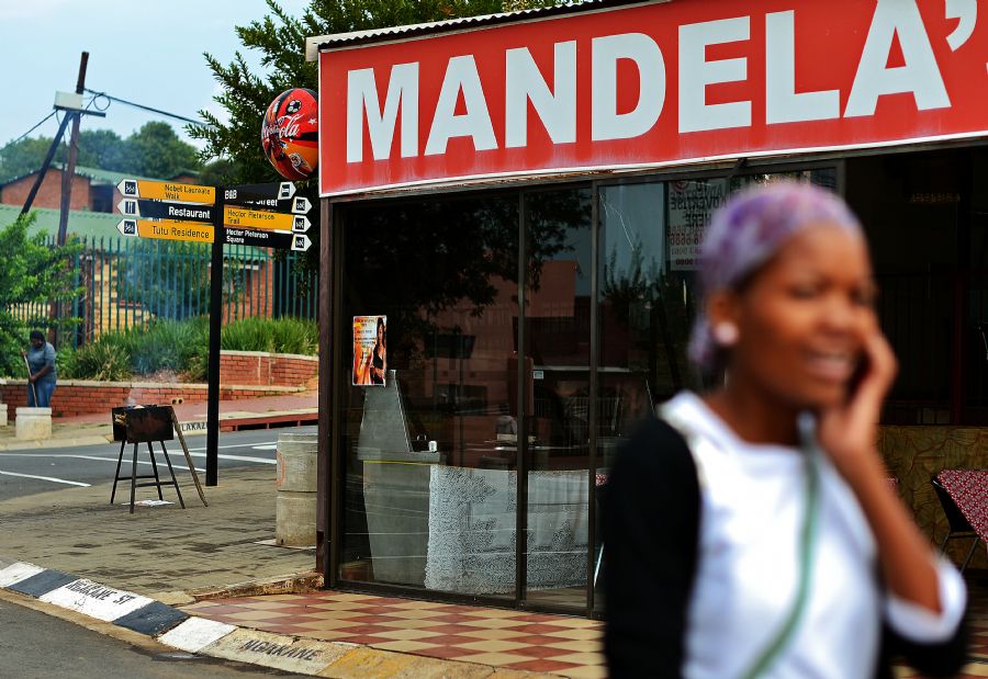 Moradora de Soweto passa por restaurante que leva o nome do ex-presidente sul-africano   / Carl de Souza/AFP