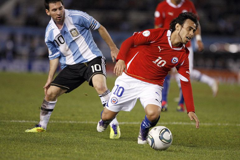 Valdivia em disputa de bola com Messi durante duelo contra a Argentina / Maxi Failla/AFP