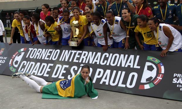 Jogadoras do Brasil fazem a festa com o troféu, enquanto Érika faz pose para as fotos